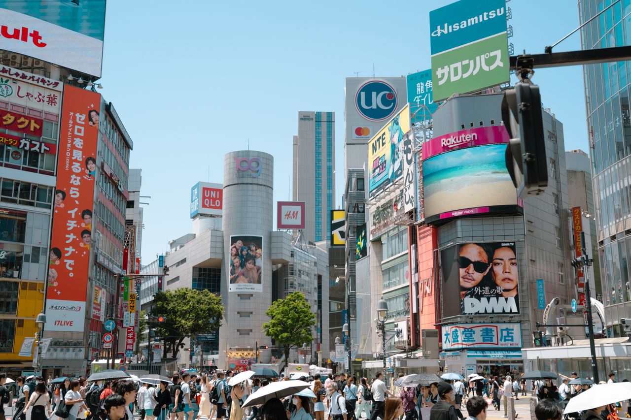 Crowded Shibuya Crossing with billboards and skyscrapers in Tokyo, a dynamic city scene.