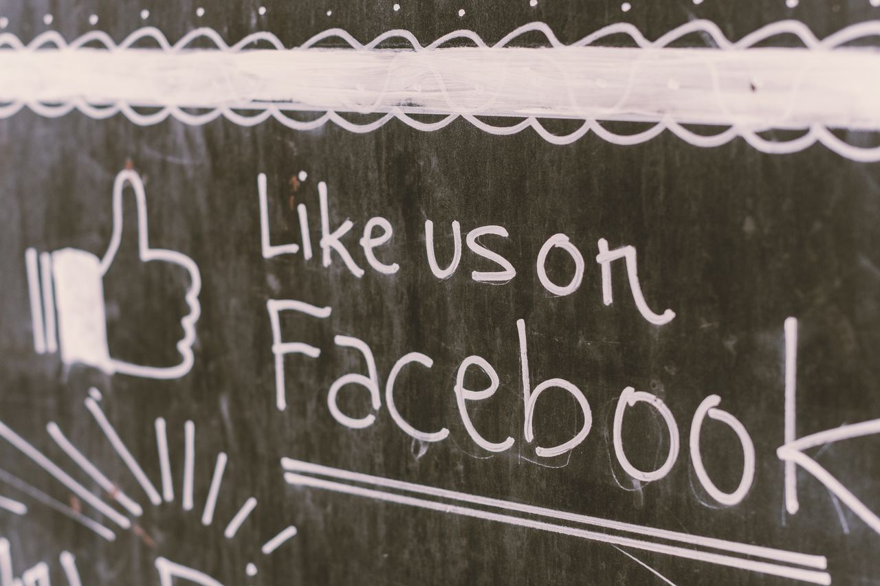 Chalkboard-style artwork encouraging Facebook interaction with a "Like us" message.